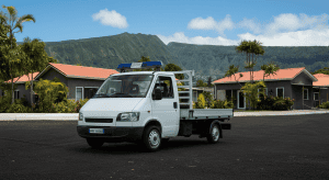 Camionnette blanche avec gyrophare devant maisons tropicales