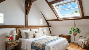 Chambre mansardée lumineuse avec poutres et fenêtre de toit